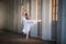 Young bayerina in a long white skirt stands in a graceful pose on pointes