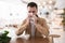 Young bearded attractive man sneezing while drinks coffee during his lunch break in the cafe, healthcare and medicine context