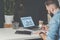 Young bearded businessman sits in office at table and laptop with inscription statistical analysis on screen