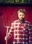 Young bearded farmer red checkered shirt with old pitchfork looking at camera