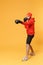 Young bearded fitness sporty guy boxer sportsman in hat, hoodie, shorts in home gym isolated on yellow background
