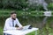 Young, bearded guy on worktable in summer, using laptop. man working, studying, surfing web. remote workplace in nature