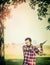 Young bearded Lumberjack with Ax gut a tree on summer nature background.