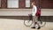 Young bearded man with bag walking with bicycle on street