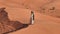 Young bearded man dressed as a shaman dancing on desert sand