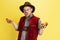 Young bearded man dressed in traditional Bavarian costume with yummy pretzels isolated over yellow background. National