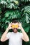 Young bearded man holding slices of orange tangerine in front of his eyes, laughing