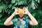 Young bearded man holding slices of orange tangerine in front of his eyes, surprised