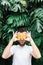 Young bearded man holding slices of orange tangerine in front of his eyes, surprised