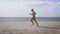 Young bearded man jogging on the sea shore at sunrise. Side portrait of healthy young bearded man running at the beach