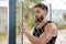 Young bearded man looking through metal urban fence