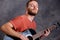 Young bearded man playing acoustic guitar