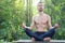 Young bearded man practicing yoga outdoor. His sitting in pose o