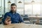 Young bearded man is sitting at table in restaurant and is using smartphone.Man looks at phone screen.