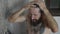 Young bearded man is washing head in a shower at home, close-up