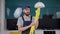 Young bearded man in workwear for cleaning kitchen puts on yellow gloves