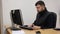 Young bearded office worker man working behind desk on computer.