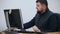 Young bearded office worker man working behind desk on computer.