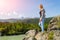 Young beatifull girl stay on a rock on a sunny warm autumn summer day resting while traveling near a green tree on the background