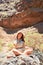 Young beauitufl hiker woman trekking natural orange mountain sitting on a stone on summer holidays