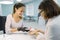 Young beautician girl manicurist talks to a female client, does manicure, chooses the color of nail polish, communicates and