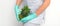 Young beautician wearing blue gloves in uniform with pineapple covers an intimate area on a white background, bikini