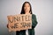 Young beautiful activist asian woman asking unity holding banner with united stand message cover mouth with hand shocked with