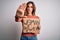 Young beautiful activist woman asking for change holding banner with united stand message with open hand doing stop sign with