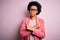 Young beautiful African American afro businesswoman with curly hair wearing pink jacket Pointing to both sides with fingers,