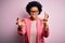 Young beautiful African American afro businesswoman with curly hair wearing pink jacket Shouting frustrated with rage, hands