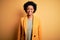 Young beautiful African American afro businesswoman with curly hair wearing yellow jacket with a happy and cool smile on face