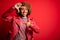 Young beautiful African American afro woman with curly hair wearing casual red jacket smiling making frame with hands and fingers