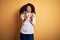 Young beautiful african american elegant woman with afro hair standing over yellow background afraid and terrified with fear