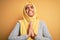 Young beautiful african american girl wearing muslim hijab over isolated yellow background begging and praying with hands together