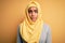 Young beautiful african american girl wearing muslim hijab over isolated yellow background depressed and worry for distress,