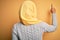 Young beautiful african american girl wearing muslim hijab over isolated yellow background Posing backwards pointing ahead with