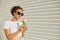 A young beautiful African-American girl in a white t-shirt and light jeans eats ice cream against a light wall on a Sunny day