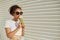 A young beautiful African-American girl in a white t-shirt and light jeans eats ice cream against a light wall on a Sunny day