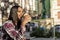 Young beautiful african american woman sitting outdoors in the city with a tablet pc while holding a take away coffee in a sunny