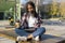 Young beautiful african american woman sitting outdoors in the city with a tablet pc while holding a take away coffee in a sunny