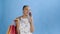 Young beautiful African using phone and holding shopping bags on blue Background in Studio. White dress with flowers