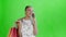 Young beautiful African using phone and holding shopping bags on green Background in Studio. White dress with flowers