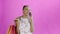 Young beautiful African using phone and holding shopping bags on pink Background in Studio. White dress with flowers