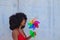 Young and beautiful Afro-American woman holds a windmill in her hands and is spinning it with the air from her lips. Summer