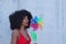 Young and beautiful Afro-American woman holds a windmill in her hands and is spinning it with the air from her lips. Summer