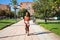 Young and beautiful Afro American woman with sculpted body training in the park, dressed in orange top and tights. Concept of