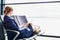 Young beautiful airport staff using digital tablet while sitting on chair during break