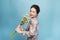 Young beautiful Aisa girl holding a bouquet on blue background