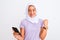 Young beautiful arabian girl wearing hijab using smartphone over isolated white background screaming proud and celebrating victory