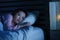 Young beautiful Asian Chinese girl lying on bed late night awake looking thoughtful suffering insomnia sleeping disorder feeling